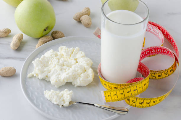 건강 한 저녁 식사, 유백색 제품, 사과, 견과류, 노란색 테이프 측정. 손실 무게의 개념, 건강 한 영양, 식사, 간식 - milky cheese 뉴스 사진 이미지