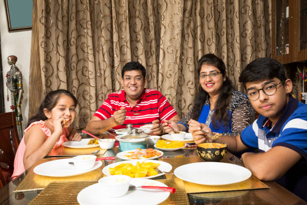 Happy family eating together at home Portrait of a happy family eating together at home - lifestyle concepts indian dinner stock pictures, royalty-free photos & images