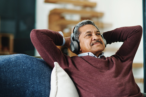 Cropped shot of a mature man wearing headphones while relaxing at home