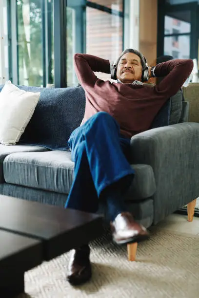Cropped shot of a mature man wearing headphones while relaxing at home