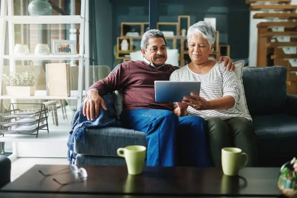 Shot of a mature couple using a digital tablet while relaxing at home