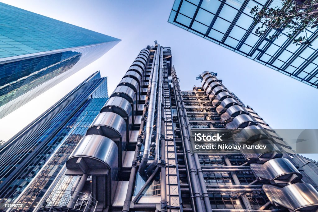 Abstract modern business buildings in financial district of London, England - stock image Extremely detailed abstract wide angle view up towards the sky in the financial district buildings of London City and its ultra modern contemporary architecture on a clear sky day. Shot on Canon EOS R full frame system with 14mm prime lens. Toned edit in blue to achieve more corporate look, image is ideal for background with plenty of copy space. Lloyds of London Stock Photo
