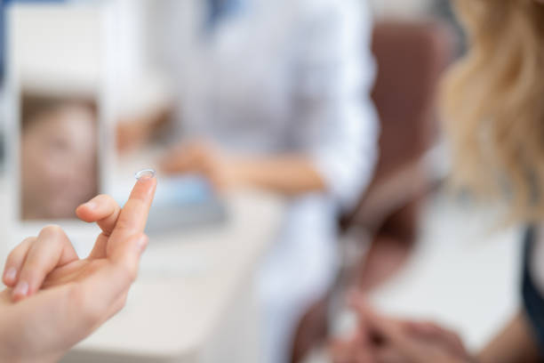 istock Child hand holding contact lens on blurred background 1135960523