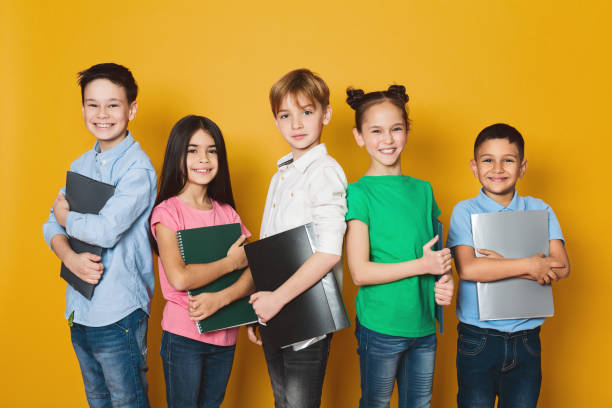 School kids with notebooks over yellow background School kids with notebooks, standing in row and looking at camera over yellow background number 5 photos stock pictures, royalty-free photos & images