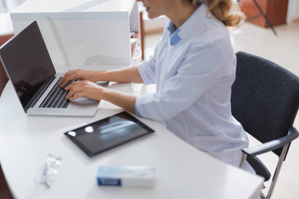 Nice professional optician using laptop while sitting at the table
