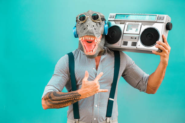 homme aîné fou dansant la musique de roche portant le masque de t-rex-le gars à la mode de tatouage ayant l'amusement écoutant la musique avec la boombox stéréo-concept absurde et drôle de tendance-focus sur le visage - london england audio photos et images de collection