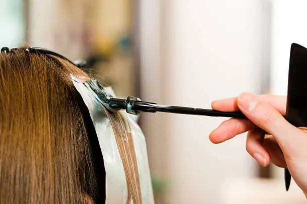 At the hairdresser – woman gets new hair colour; close-up on strand of hair