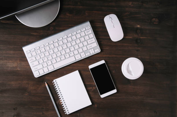 istock White keyboard, mouse and Notepad on wooden background. Flat lay and top view 1135963770