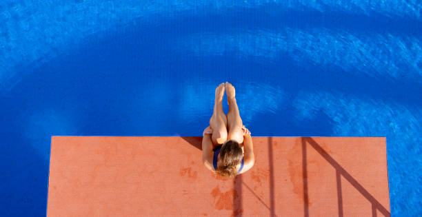 istock Young woman sitting on diving board 1135964346