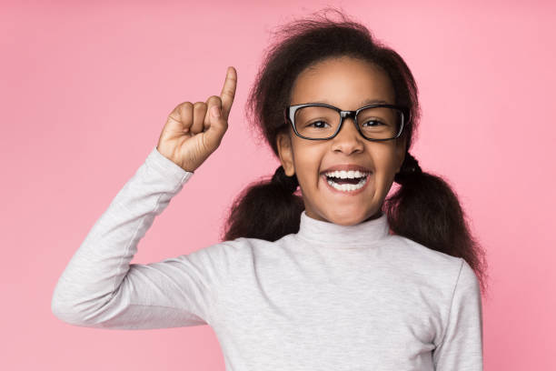 szczęśliwy dzieciak w okularach ma pomysł, podnosząc palec - glasses child little girls african ethnicity zdjęcia i obrazy z banku zdjęć