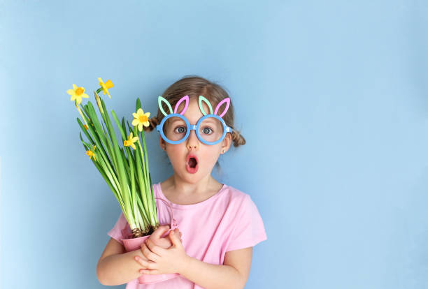 little child wearing bunny ears glasses and holding flowers on easter day. - glasses child cute offspring imagens e fotografias de stock