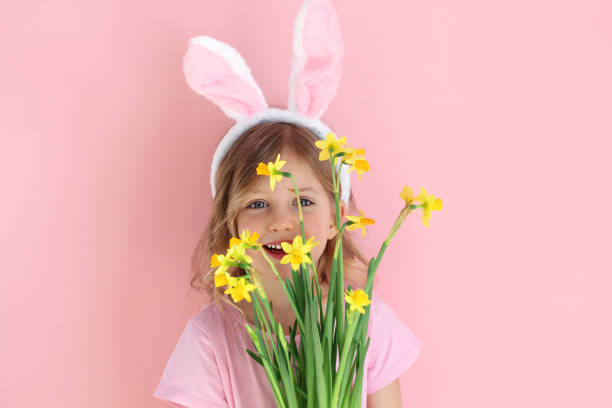 istock child wearing bunny ears holding flowers on Easter day . 1135968600