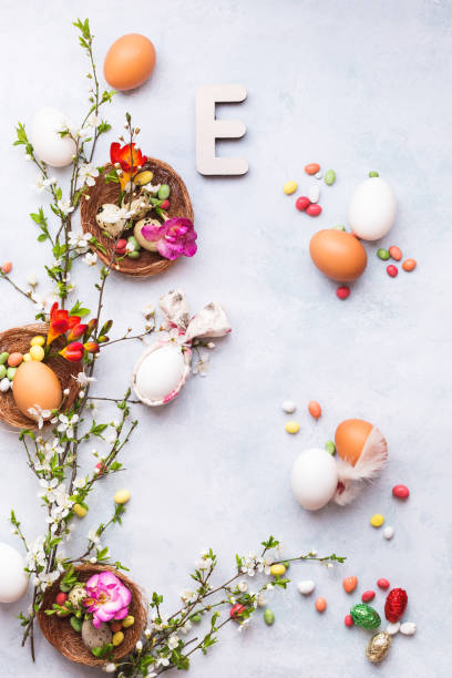 fondo de pascua con varios huevos, servilleta de orejas de conejo, rama flor de primavera, caramelos y la letra de pascua e en la superficie texturizada - easter text single word paint fotografías e imágenes de stock