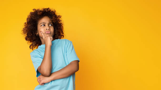 istock Let me think. Doubtful, thoughtful child girl posing over background 1135969533