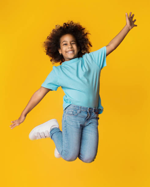Little african-american girl jumping over studio background Little african-american girl jumping over yellow studio background jumping stock pictures, royalty-free photos & images