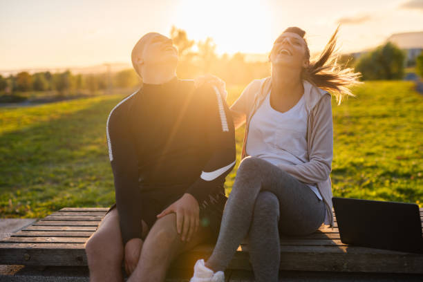 Happy young pregnant couple sitting on the bench and laughing.