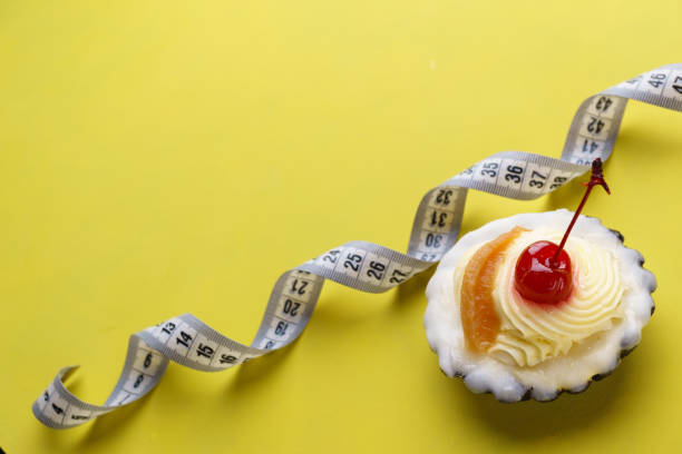 istock diet concept. sweet cupcake and measure tape 1135971026