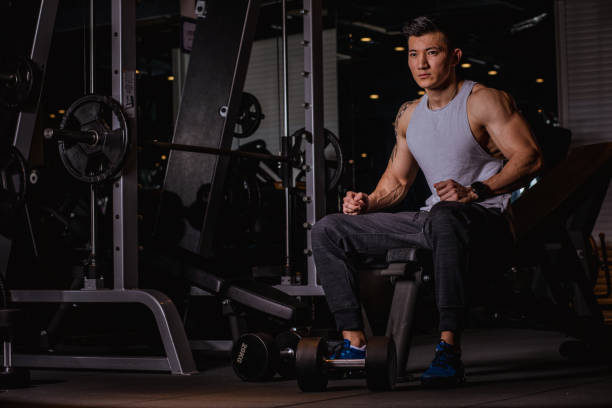 istock Fit Chinese guy sitting alone in gym 1135971407