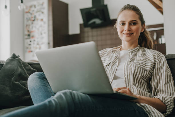 istock Young smiling female working on laptop at home 1135976485