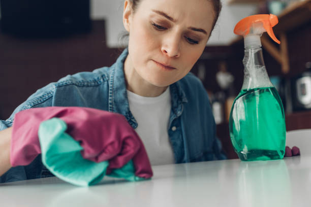 istock Young female trying to clean table surface at home 1135976510