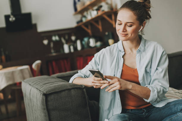 istock Relaxed lady sitting on sofa with smartphone 1135976559