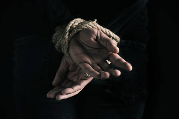 man with his hands tied behind his back - tied up imagens e fotografias de stock