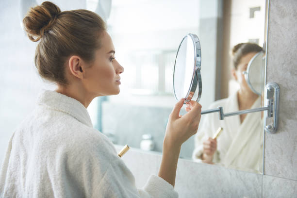 istock Lady looking at small round vanity glass mirror 1135983046