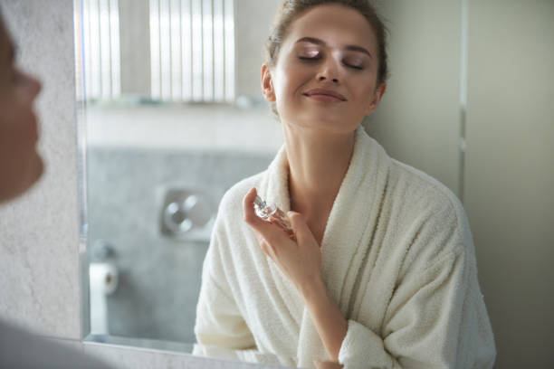 joven sonriente dama disfrutando de su perfume en la mañana - perfumado fotografías e imágenes de stock