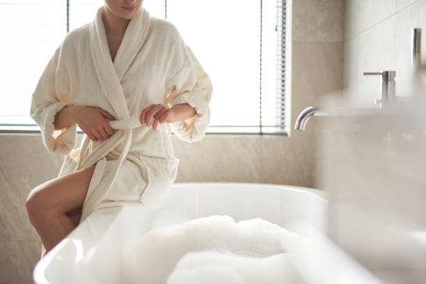 istock Lady untying belt of bathrobe to take bath 1135985992