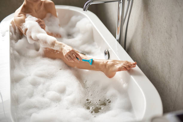istock Young lady shaving legs in foam bath 1135986012