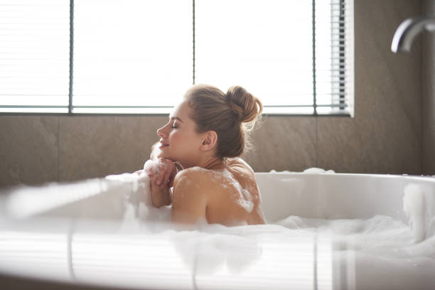 Young pretty lady leaning on ledge of bath tub stock photo