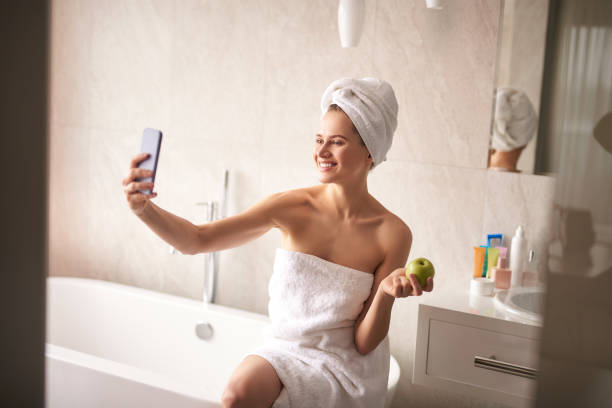 istock Happy lady making selfie by phone in bathroom 1135986048