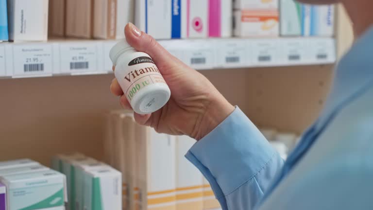 Woman reaching for the vitamin bottle on the shelf at the chemist's and checking the label