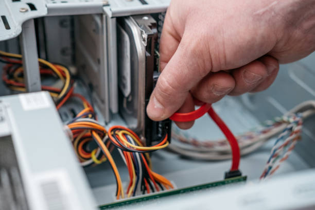 istock Hand of man plugging SATA (Serial AT Attachment, Serial ATA) data cable in hard drive device. Computer bus interface to connect mass storage devices, close up view. 1135986478