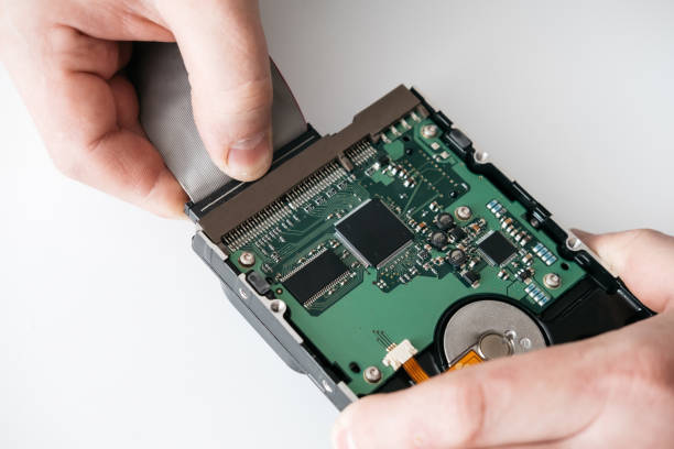 istock Hard disk recovery service, hands of repairman holding broken hdd with bad sectors. Computer engineer performs urgent repairs recovery of lost data during deletion HDD 1135986576