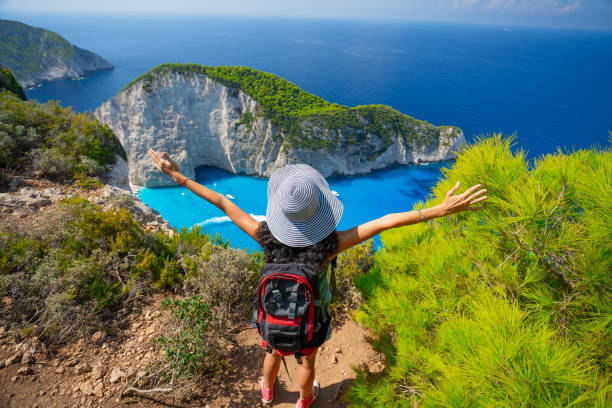 istock Backpacker standing arms outstretched and looking the sea 1135989480