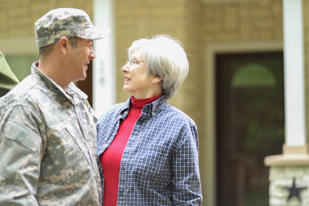 Family welcomes home USA army soldier. Family welcomes home a USA army soldier. Mother excitedly hugs adult son, who wears combat uniform and carries duffle bag. They stand in front of mother's home. proud army mom stock pictures, royalty-free photos & images