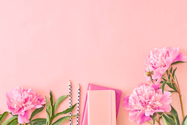 istock Flat lay blogger or freelancer workspace with a notebook and pink peonies on a pink background 1135990636