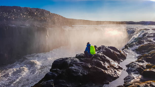 istock Iceland - man squating next to the waterfall 1135991028
