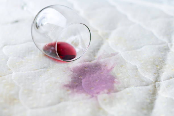 vaso de vino derramado en la cama. el wineglass accidentalmente caído en la sábana blanca. mala suerte, situación lamentable. mancha húmeda. - glass broken spilling drink fotografías e imágenes de stock