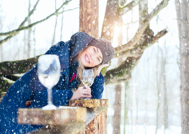 Woman drinking wine in log cabin in snowy day stock photo