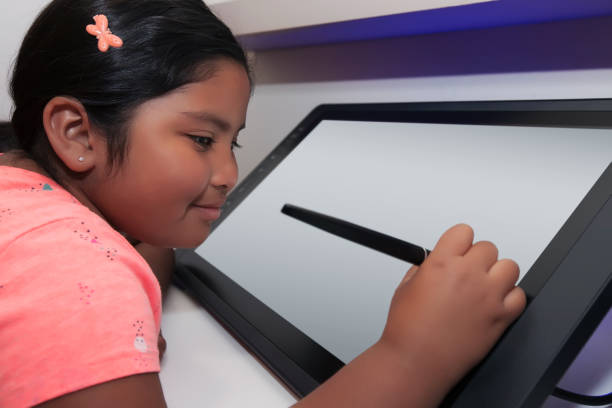 istock Elementary school student holding a pen like stylus and drawing on a digital drawing tablet. 1135999831