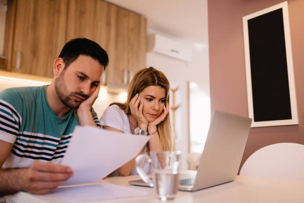 istock Worried young couple analyzing bills while sitting in kitchen 1136001353