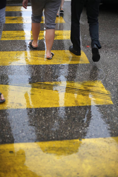 Motion blurred, pedestrians crossing street on zebra crossing.