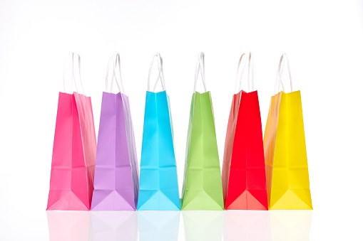 pink, violet, blue, green, red and yellow paper bags on glas, copy space available