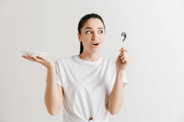 istock Young fun crazy brunette housewife with spoon isolated on white background 1136005388