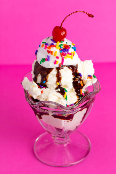 istock Vanilla Sundae with Sprinkles and Chocolate Sauce on a Pink Background 1136006677