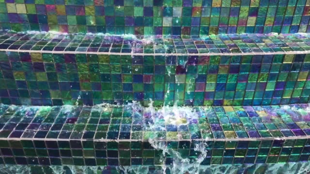 Water flows over shimmer tile textured fountain in Aruba