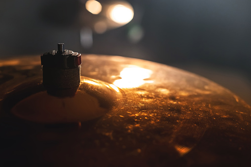 Close-up Drum set in a dark room against the backdrop of the spotlight. Atmospheric background symbol of playing rock or jazz drums. Copper plates on a cold background.