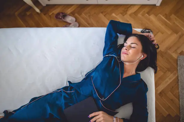 Photo of Sleeping beauty in bed relaxing with headphones and a book